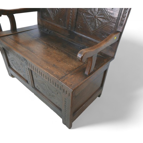 341 - An oak hall bench with a carved panel back and lift up seat, 106 by 57 by 105cm high.