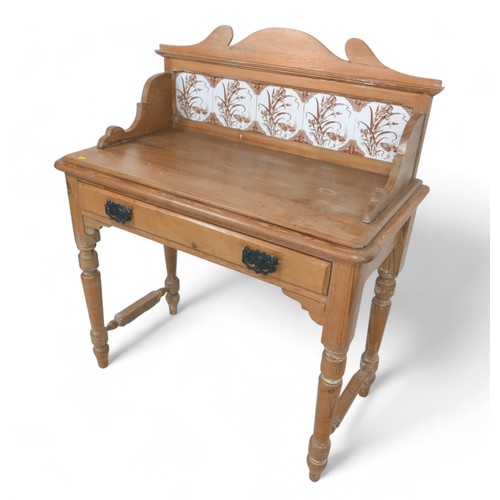 317 - A Victorian stripped pine washstand, with a tiled back and frieze drawer on turned legs, 90 by 48 by... 