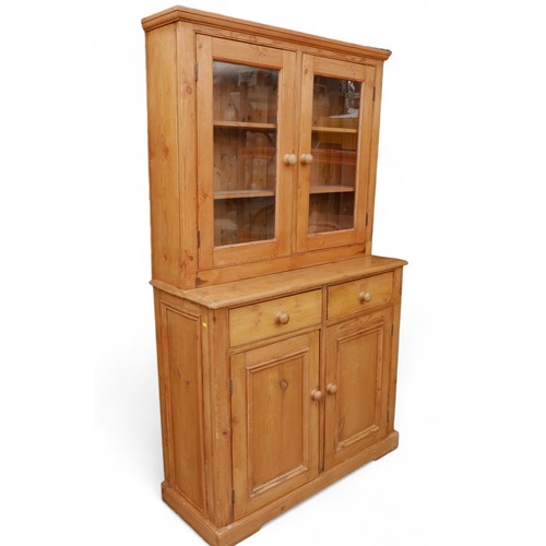 354 - A stripped pine kitchen dresser, with a two door glazed top over a two drawer two door base, 119 by ... 