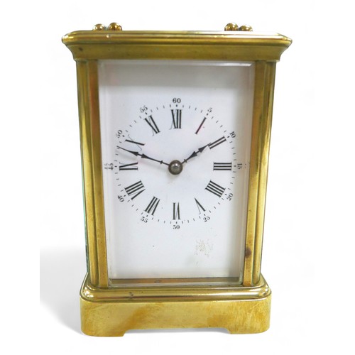 176 - A brass carriage clock, striking on a gong, 8 by 7 by 12cm high with handle down, with key and runni... 