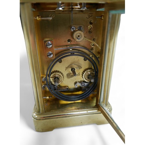 176 - A brass carriage clock, striking on a gong, 8 by 7 by 12cm high with handle down, with key and runni... 