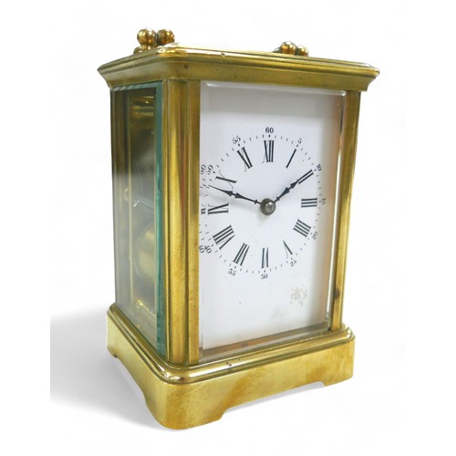 176 - A brass carriage clock, striking on a gong, 8 by 7 by 12cm high with handle down, with key and runni... 