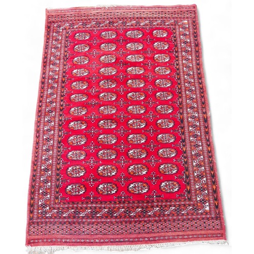 281 - A hand knotted woolen rug with red field and elephant foot design, 123 by 195cm.