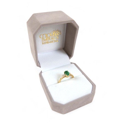 85 - A 14k yellow gold Colombian emerald ring, the oval cut stone 7 by 5 by 4mm, flanked by two 2mm princ... 