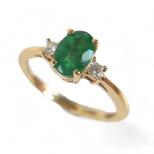 85 - A 14k yellow gold Colombian emerald ring, the oval cut stone 7 by 5 by 4mm, flanked by two 2mm princ... 