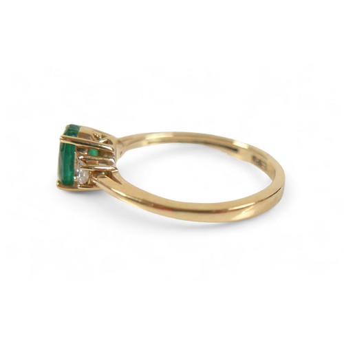 85 - A 14k yellow gold Colombian emerald ring, the oval cut stone 7 by 5 by 4mm, flanked by two 2mm princ... 