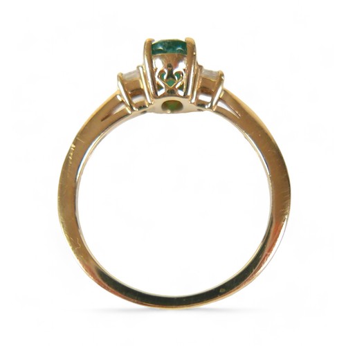 85 - A 14k yellow gold Colombian emerald ring, the oval cut stone 7 by 5 by 4mm, flanked by two 2mm princ... 