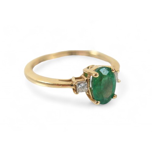 85 - A 14k yellow gold Colombian emerald ring, the oval cut stone 7 by 5 by 4mm, flanked by two 2mm princ... 