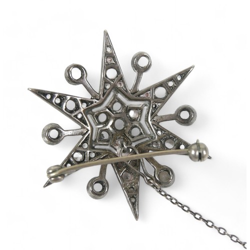 71 - A zircon and white metal starburst brooch, with safety chain,  4 by 3cm.