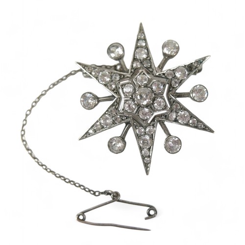 71 - A zircon and white metal starburst brooch, with safety chain,  4 by 3cm.