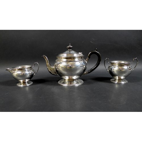 4 - A George V silver three piece tea service, comprising teapot on circular foot, with ebonized handle,... 