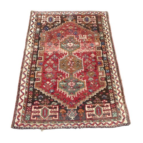 315 - A small woolen rug with red ground, stepped corners, crenellated design, brown spandrels, cream ribb... 