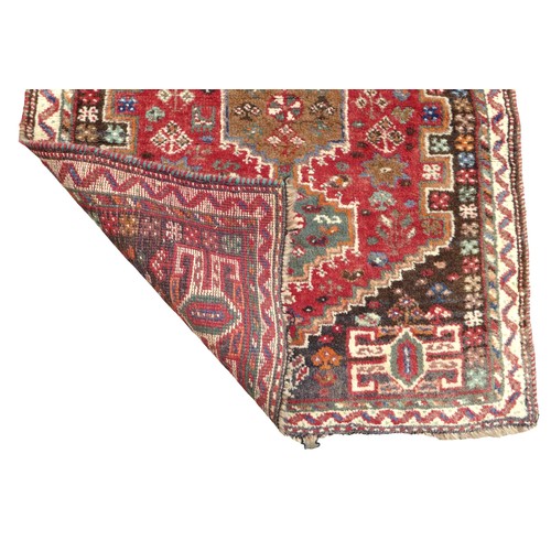 315 - A small woolen rug with red ground, stepped corners, crenellated design, brown spandrels, cream ribb... 