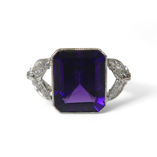 9 - An amethyst and diamond platinum ring, the emerald cut amethyst 8 by 10mm, surrounded by round cut d... 