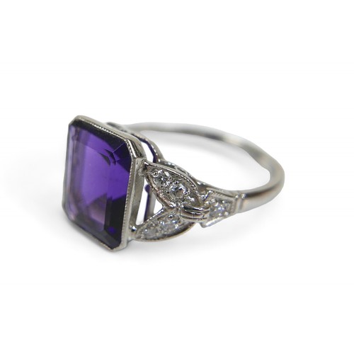 9 - An amethyst and diamond platinum ring, the emerald cut amethyst 8 by 10mm, surrounded by round cut d... 