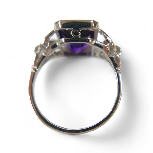 9 - An amethyst and diamond platinum ring, the emerald cut amethyst 8 by 10mm, surrounded by round cut d... 