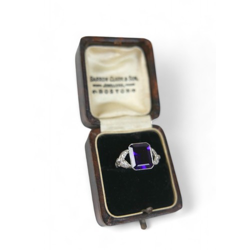 9 - An amethyst and diamond platinum ring, the emerald cut amethyst 8 by 10mm, surrounded by round cut d... 