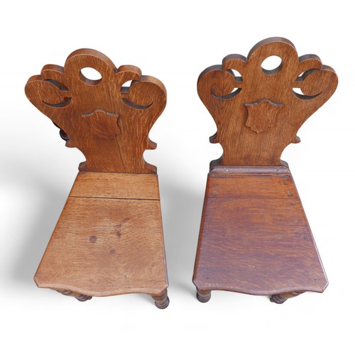 329 - A pair of Victorian oak hall chairs, on turned front legs, carved top rail and shield backs, ....