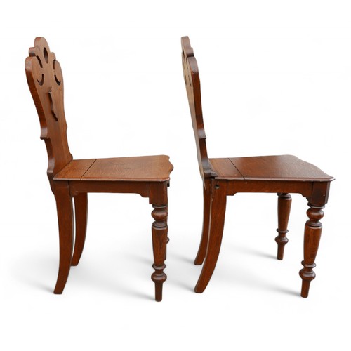 329 - A pair of Victorian oak hall chairs, on turned front legs, carved top rail and shield backs, ....