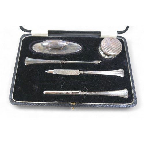 72 - A boxed part silver manicure set and four items of silver, comprising two napkin rings, a toast rack... 