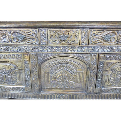 357 - An antique carved oak dresser base, dated 1675 with three frieze drawers above two cupboard doors an... 