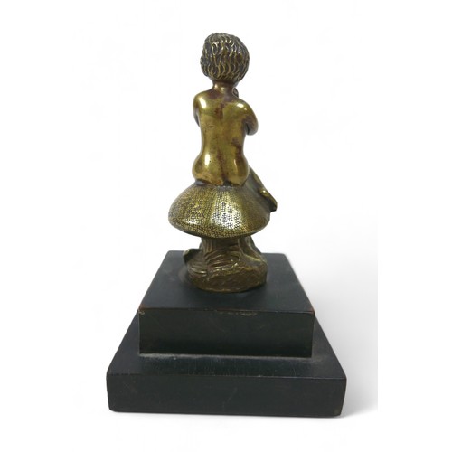 188 - A brass car mascot in the form of a boy sitting on a mushroom, on a wooden base 11 by 11 by 17cm hig... 