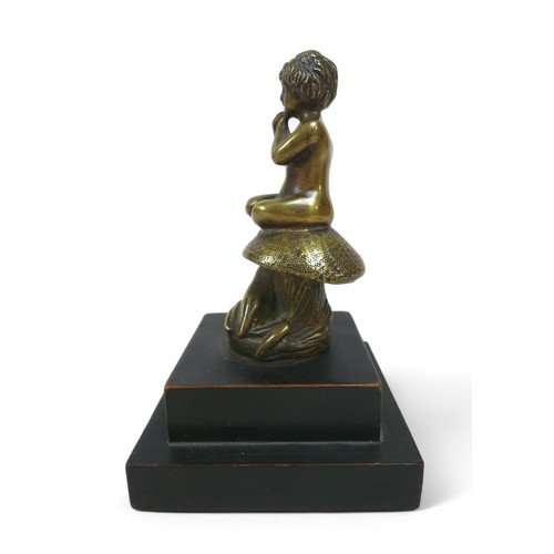 188 - A brass car mascot in the form of a boy sitting on a mushroom, on a wooden base 11 by 11 by 17cm hig... 