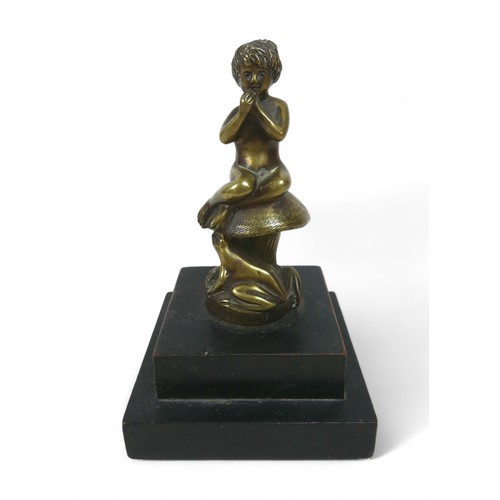 188 - A brass car mascot in the form of a boy sitting on a mushroom, on a wooden base 11 by 11 by 17cm hig... 