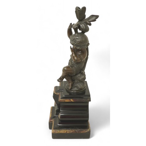 170 - A bronze figure of a putti on a rocky outcrop on marble base, 20 by 15 by 45cm high.