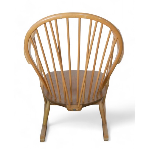 332 - An Ercol beech stick back rocking chair, together with an upholstered footstool. (2)