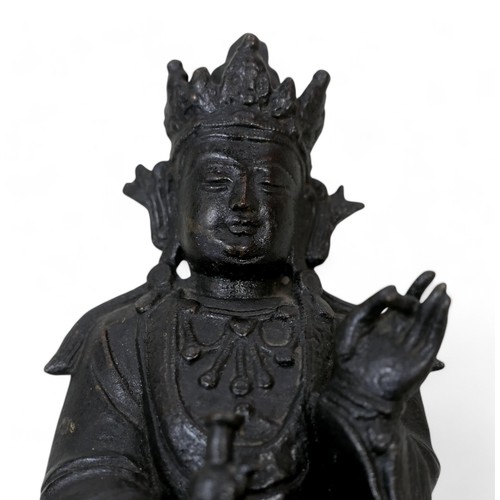 214 - A bronzed sculpture of Guanyin in a seated position, 21cm high.