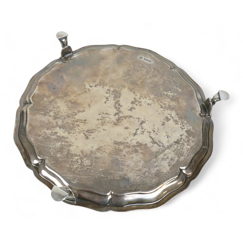 123 - A George V silver salver, with scalloped rim and beaded edging, raised on three hoof feet, Hawkswort... 