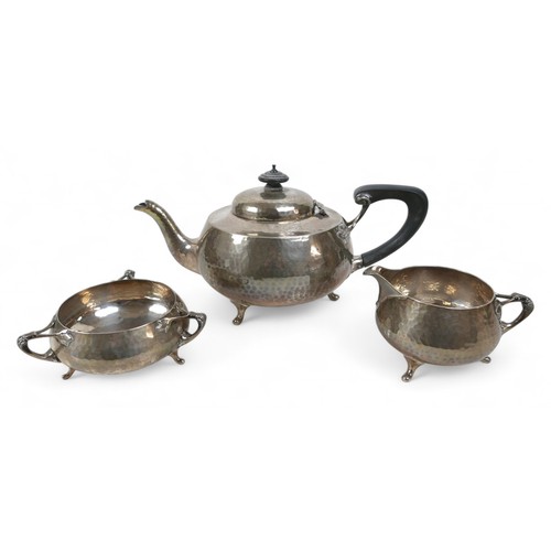 134 - An Arts & Crafts three piece tea set, comprising teapot, 29 by 16 by 15.5cm high, milk jug, 13 by 9 ... 