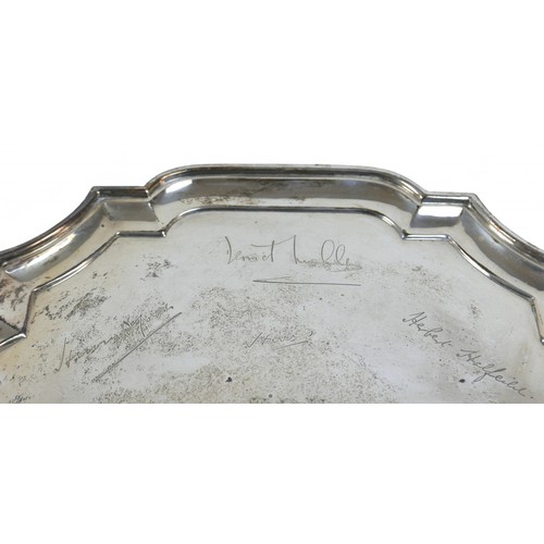 129 - A silver tray, London, four scroll feet and shaped pie crust edge, engraved with names, Goldsmiths a... 