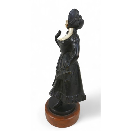 217 - An early 20th century bronze and ivory figure, modelled as a girl in a bonnet with flower basket, st... 