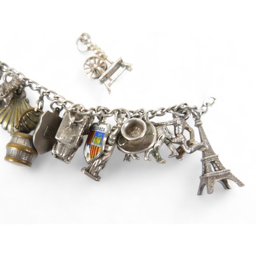 38 - A silver charm bracelet, with multiple charms, including an Eiffel Tower, Statue of Liberty, railway... 