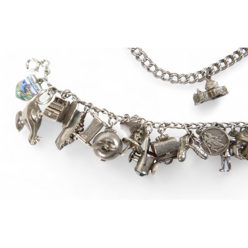 38 - A silver charm bracelet, with multiple charms, including an Eiffel Tower, Statue of Liberty, railway... 