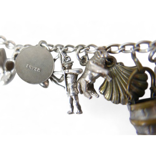 38 - A silver charm bracelet, with multiple charms, including an Eiffel Tower, Statue of Liberty, railway... 