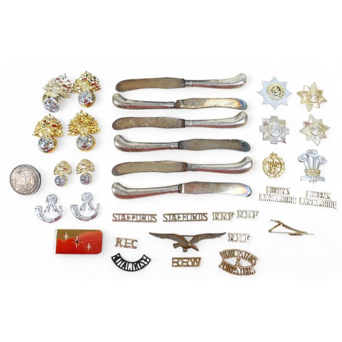 30 - Silver ware and military badges, comprising six pistol grip knives, a photo frame, 1880 dollar brooc... 