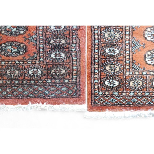 329 - A pair of hand knotted woolen rugs, with rust coloured field, 65 by 100cm. (2)