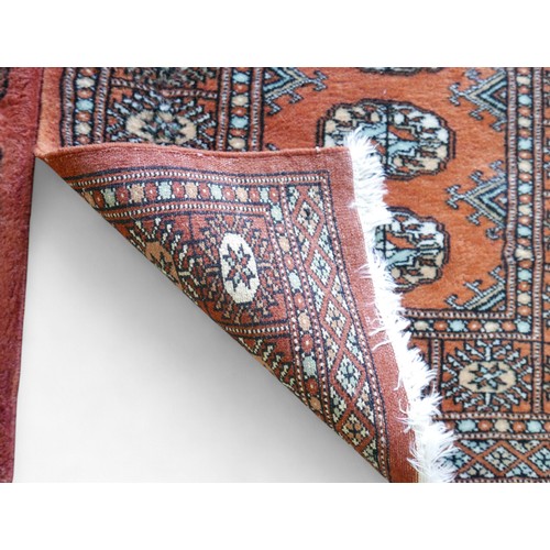 329 - A pair of hand knotted woolen rugs, with rust coloured field, 65 by 100cm. (2)