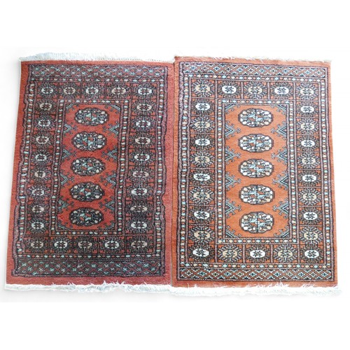 329 - A pair of hand knotted woolen rugs, with rust coloured field, 65 by 100cm. (2)