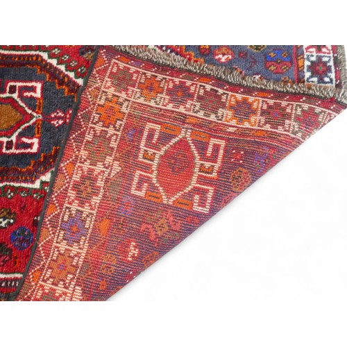 363 - A hand knotted woolen rug with a blue field, 115 by 170cm.