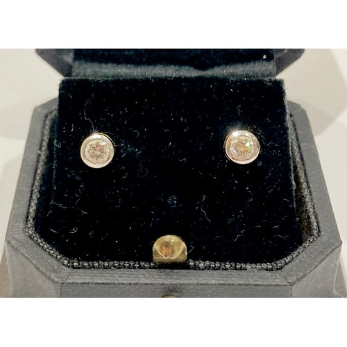 58A - A pair of 18ct white and yellow gold diamond stud earrings, each round brilliant cut stone, approxim... 