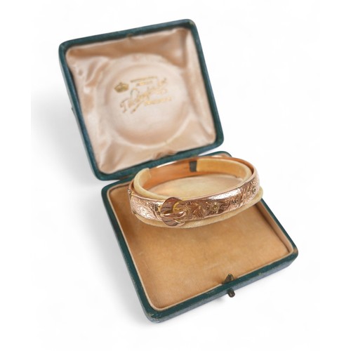 78 - A 9ct rose gold hollow bangle, in the form of a belt, 7 by 6 by 1cm external, with box, 11.3g.