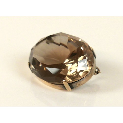 40 - A 14k gold and smoky quartz brooch, set with an oval faceted stone, on gold mount with claw setting,... 