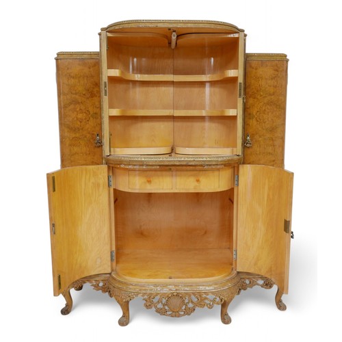 325 - A 20th century blonde burr walnut cocktail drinks cabinet, with two bow fronted doors enclosing a fi... 