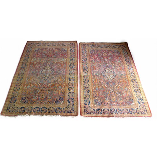 332 - A pair of hand knotted woolen Kashan Persian rugs, with a central medallion on a red field and styli... 