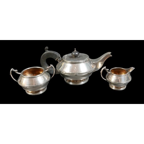 29 - A George V silver three piece tea service, of compressed ovoid form on a circular foot, with a decor... 