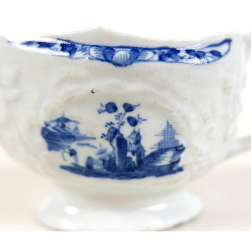 137 - An 18th century Lowestoft porcelain small sauce boat, decorated with moulded exterior and in undergl... 